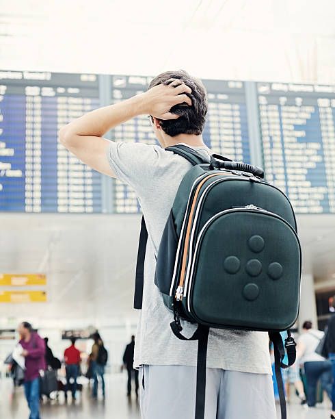 Jet-lagged traveler at airport surrounded by time zone clocks