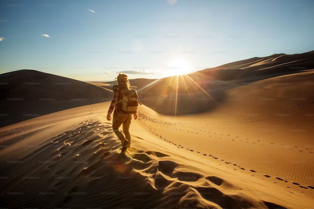 A dehydrated tourist slumped in the desert, showing visible signs of heat exhaustion and fatigue